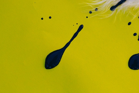 Splash of black watercolor paint on a yellow surface