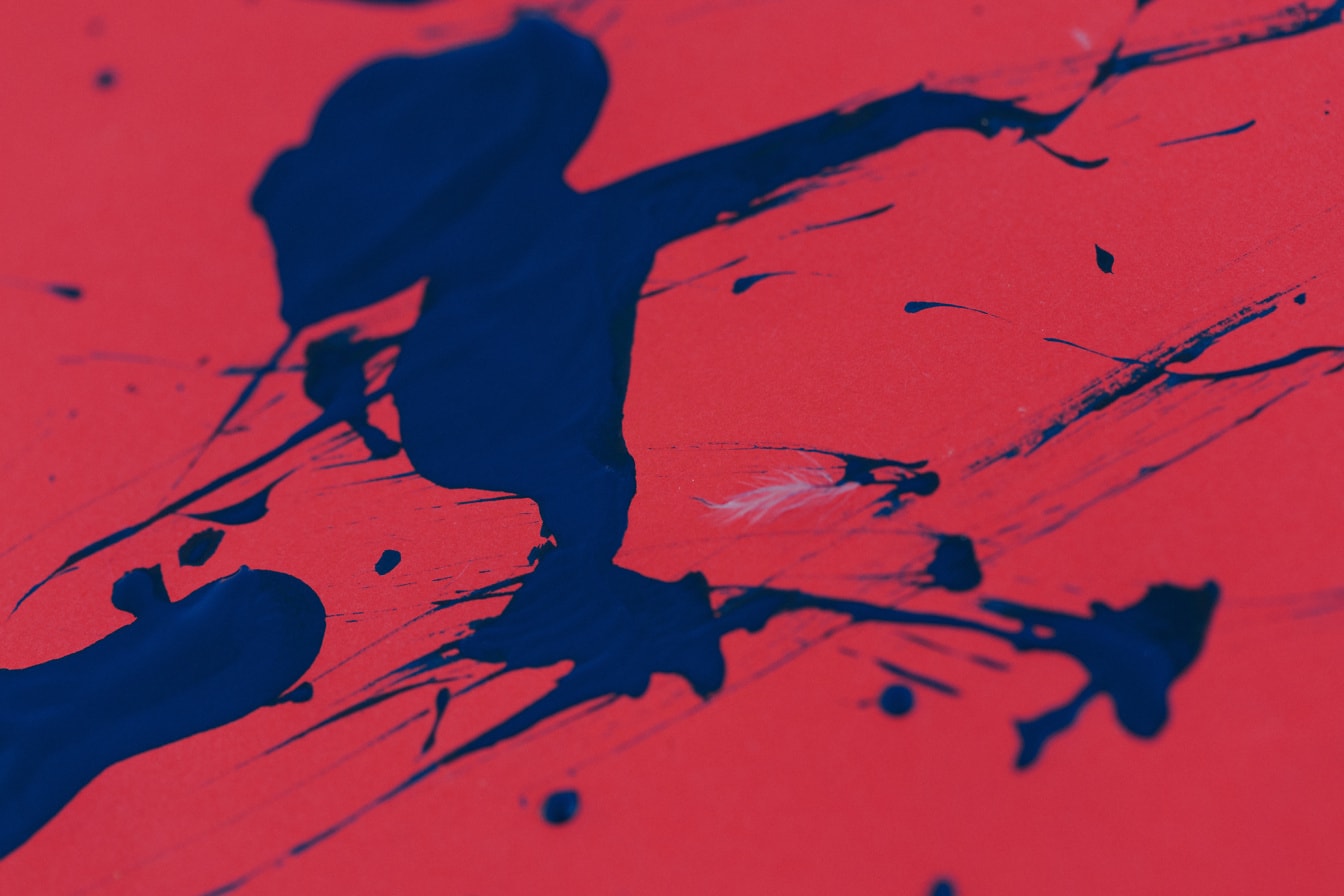 Respingo abstrato de tinta azul escuro em uma superfície vermelha escura