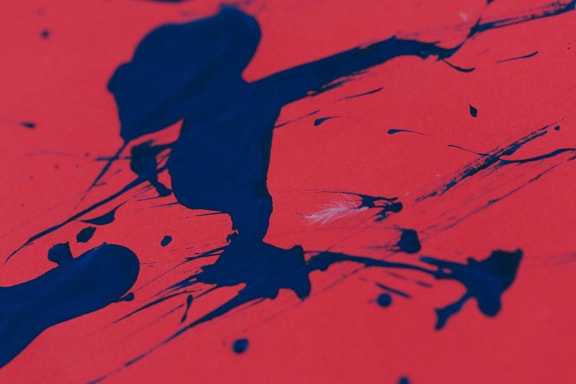 Éclaboussure de peinture abstraite bleu foncé sur une surface rouge foncé