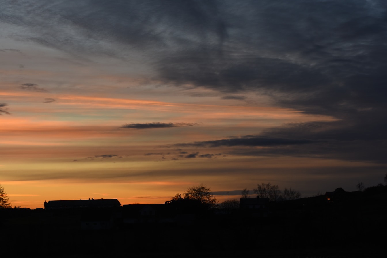 Silhouet van regeling bij zonsondergang met zwarte wolken