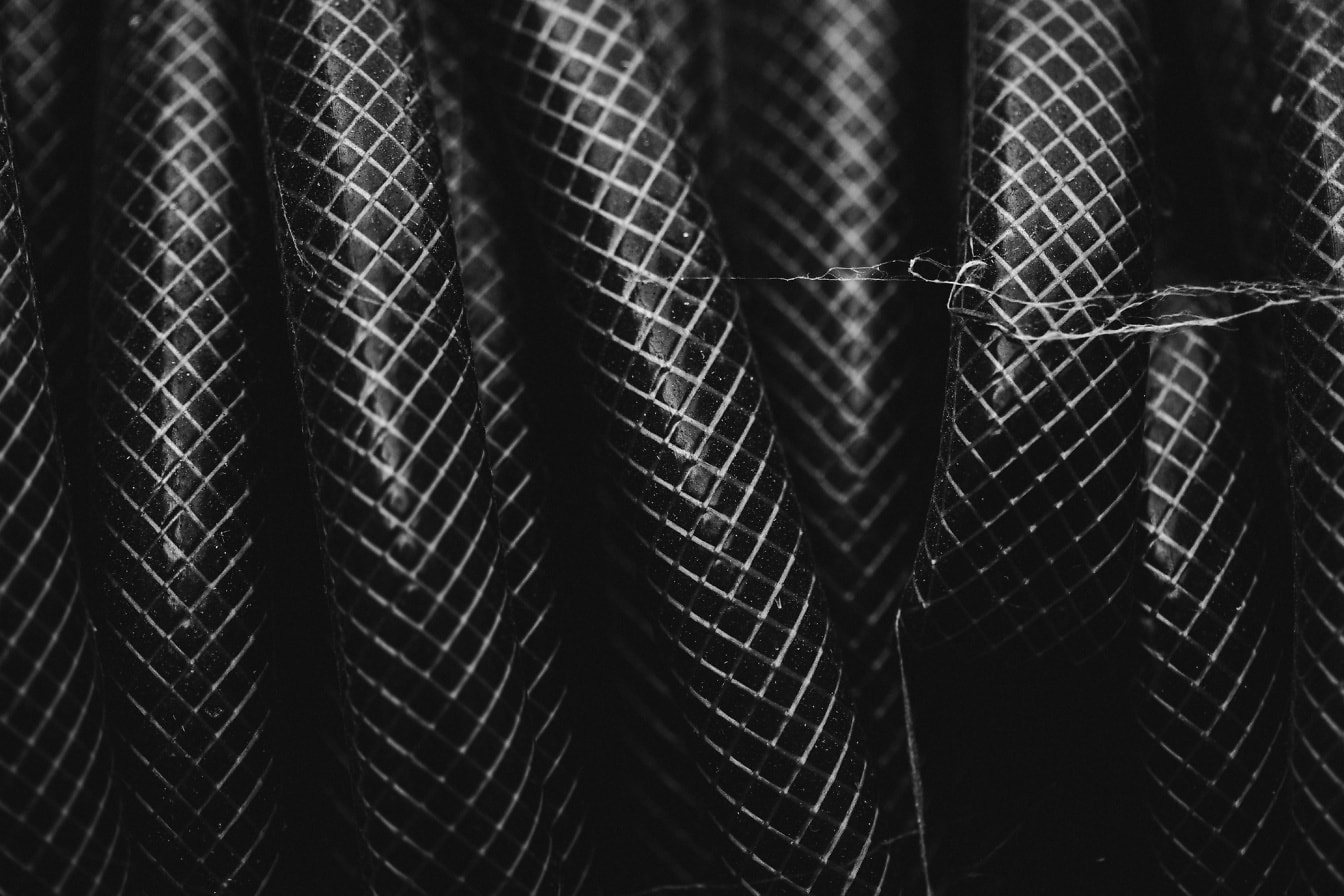 Close up black and white photo of plastic garden hose texture
