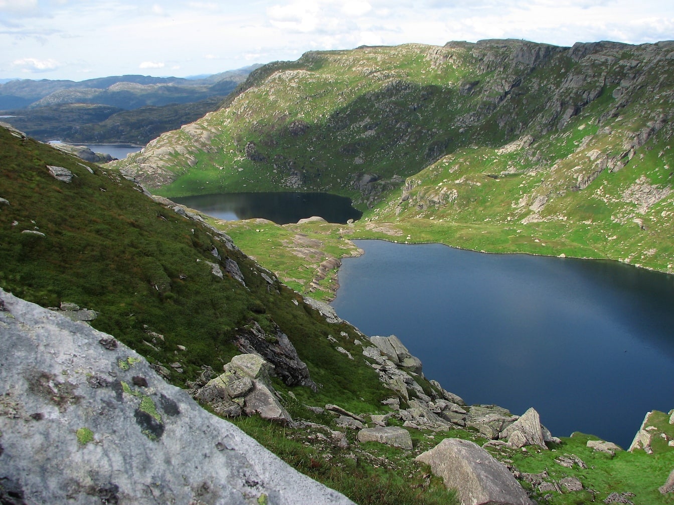 Панорамний вид з вершини пагорба на озеро, оточене горами навесні
