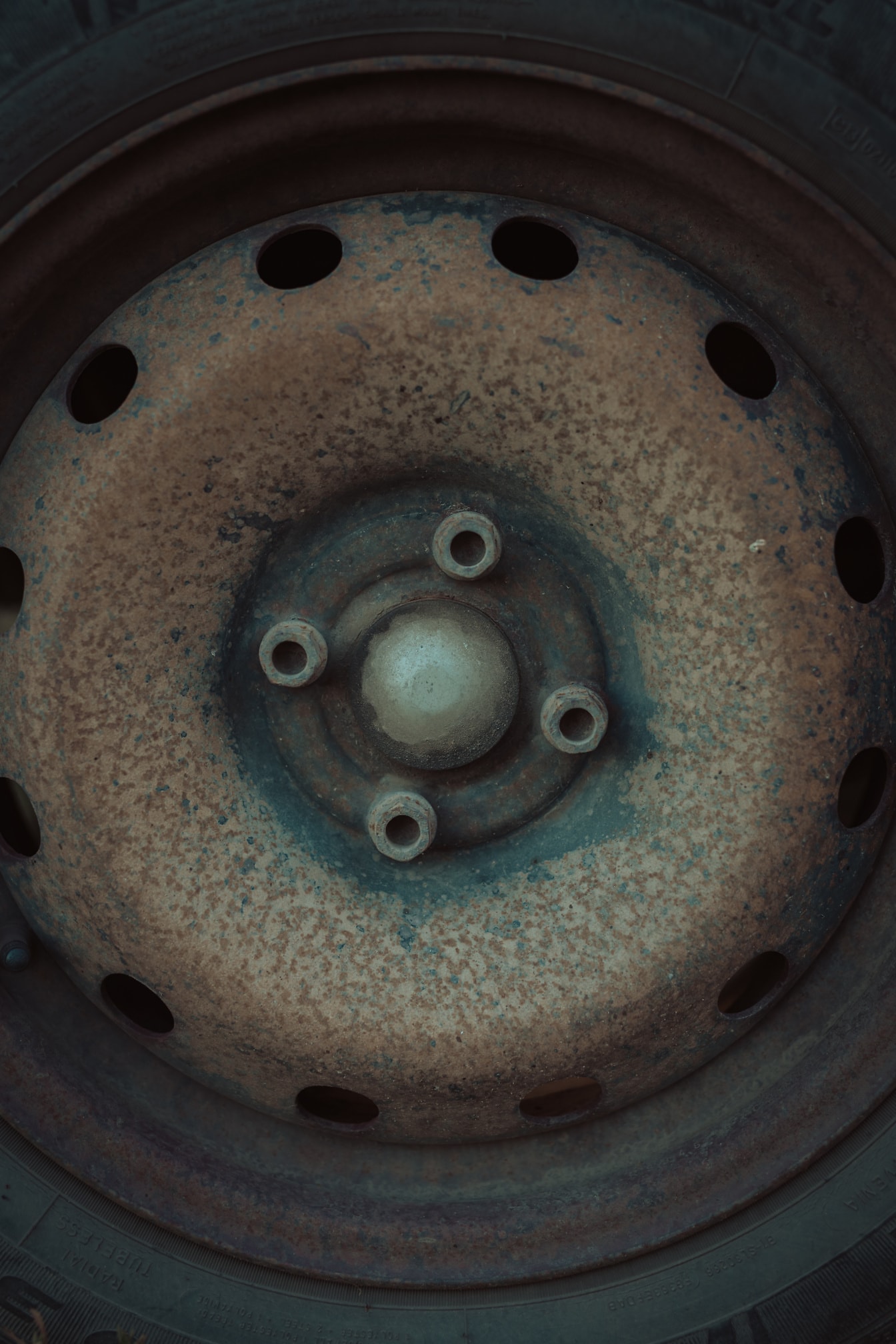 Primer plano de una rueda oxidada con tornillos de hierro