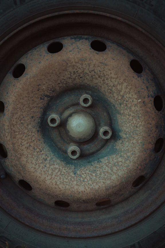 Close up of a rusty wheel with iron screws on it