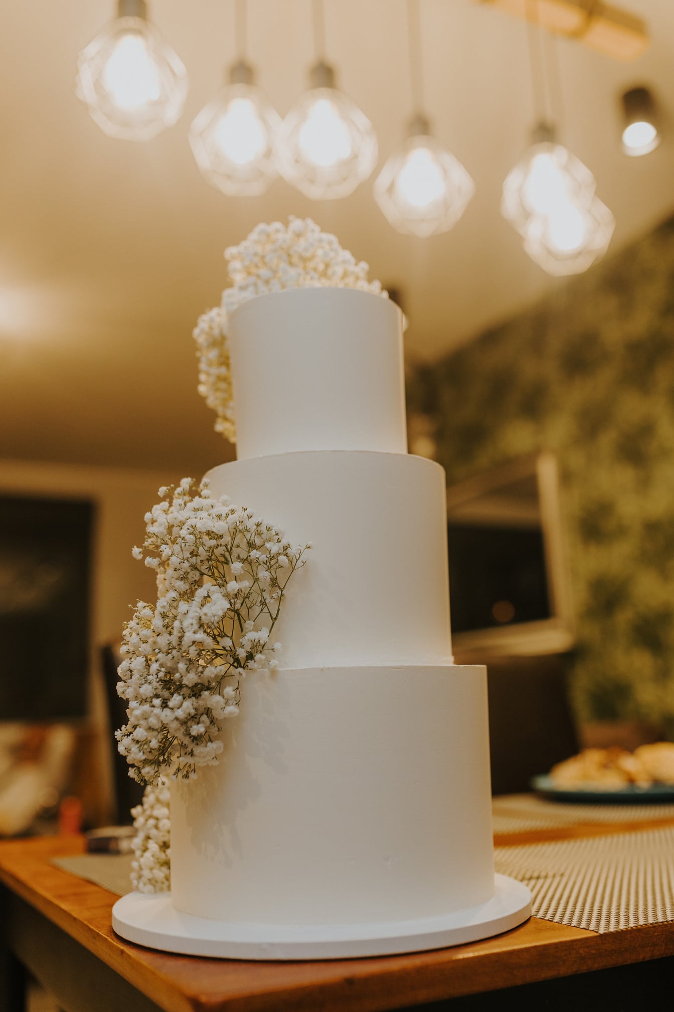 三层白色婚礼蛋糕，上面有鲜花