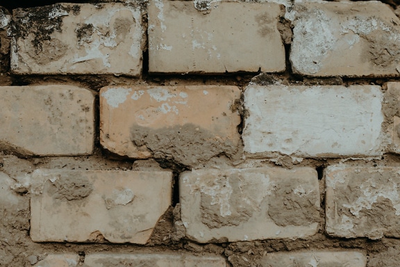 Horizontal brick masonry wall with dry soil as mortar close-up texture