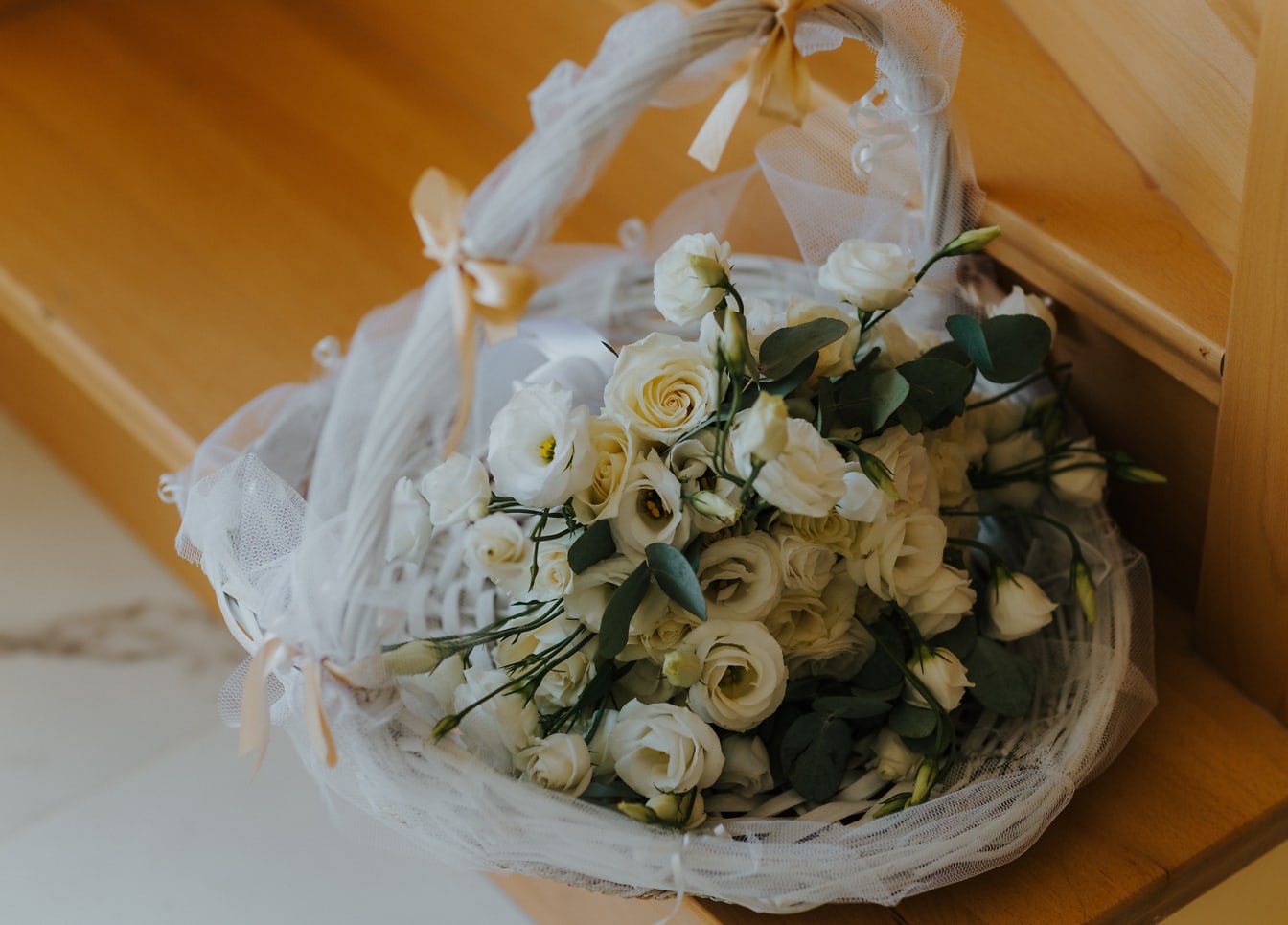 Плетена кошница от бели рози на дървено стълбище