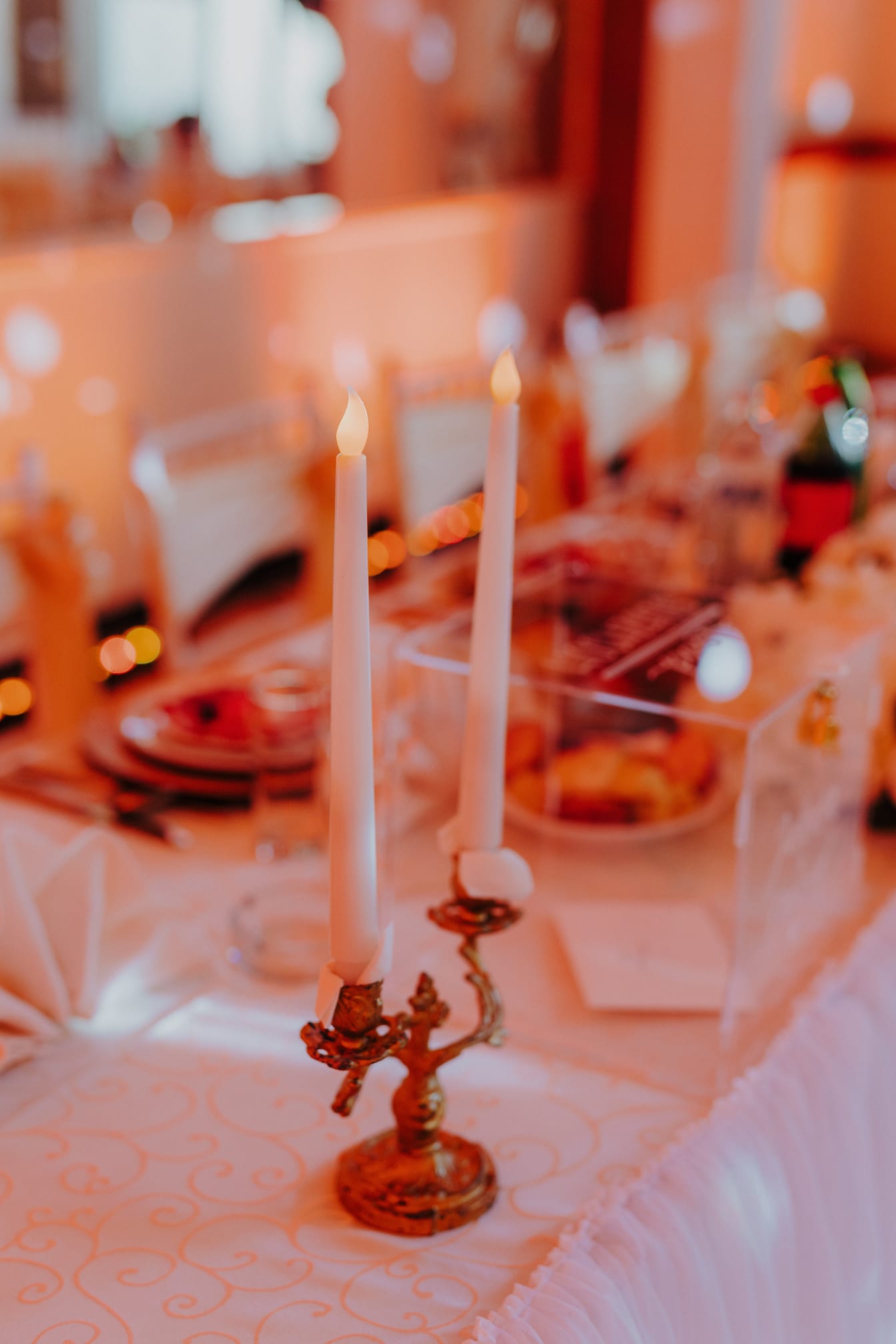 Umelé biele sviečky s falošnými plameňmi na stole v mieste konania svadby