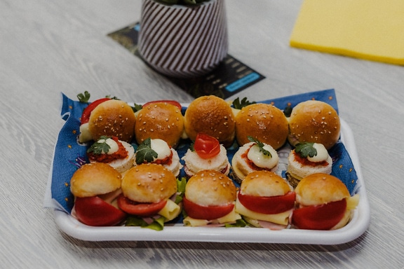 Bakke med miniature sandwich og burgere på et bord