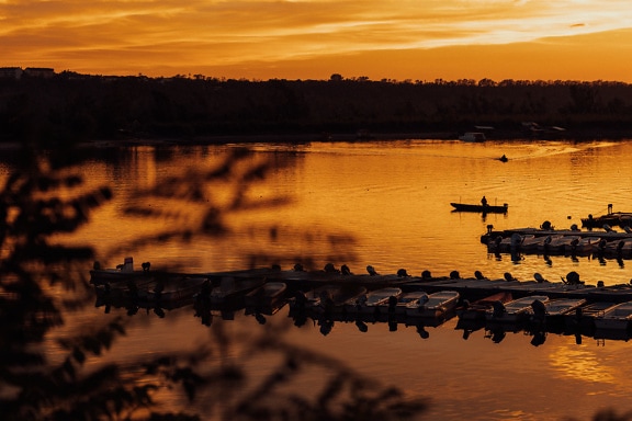 Silhouette de bateaux sur un lac de Tikvara au coucher du soleil