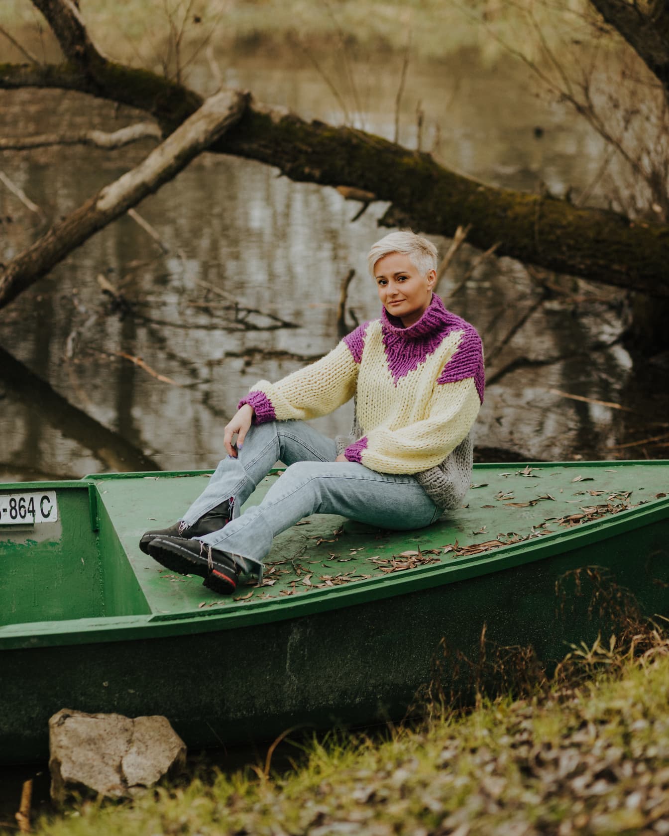 Adorabile donna bionda in maglione di lana fatto a mano seduta su una barca