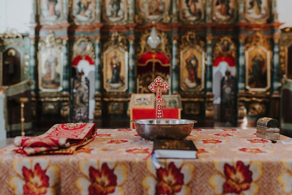 Skål och en bibelbok på ett bord som förberetts för dopritual i ortodoxa kyrkan