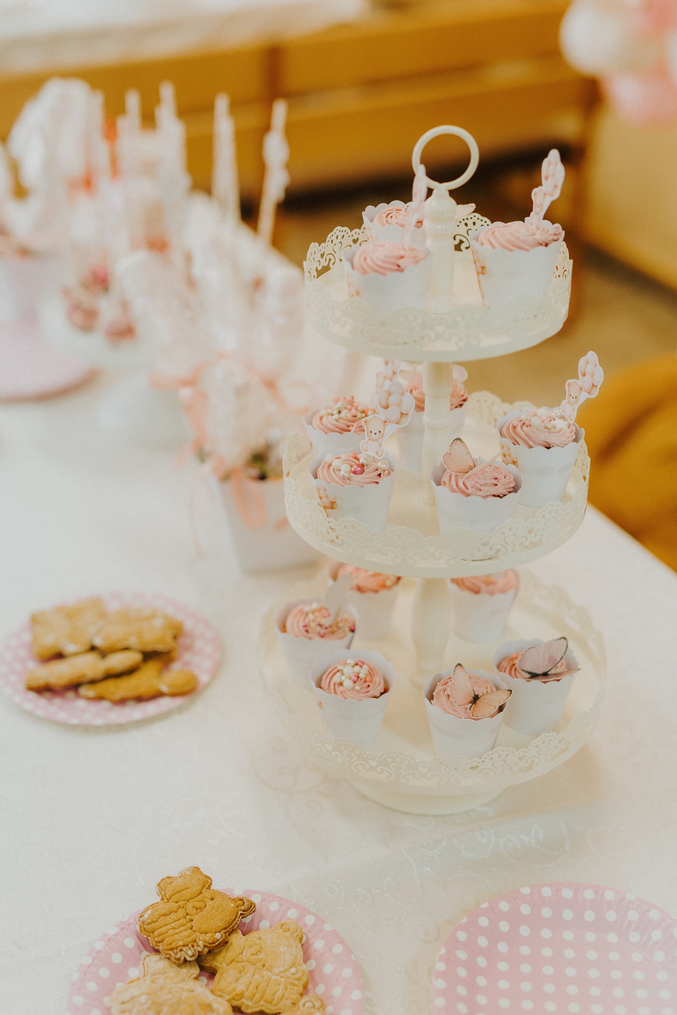 Elegant serveringsbricka i tre nivåer med rosa krämiga cupcakes