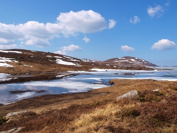 Landskap av fjellelv med smeltende is på overflaten av kaldt vann