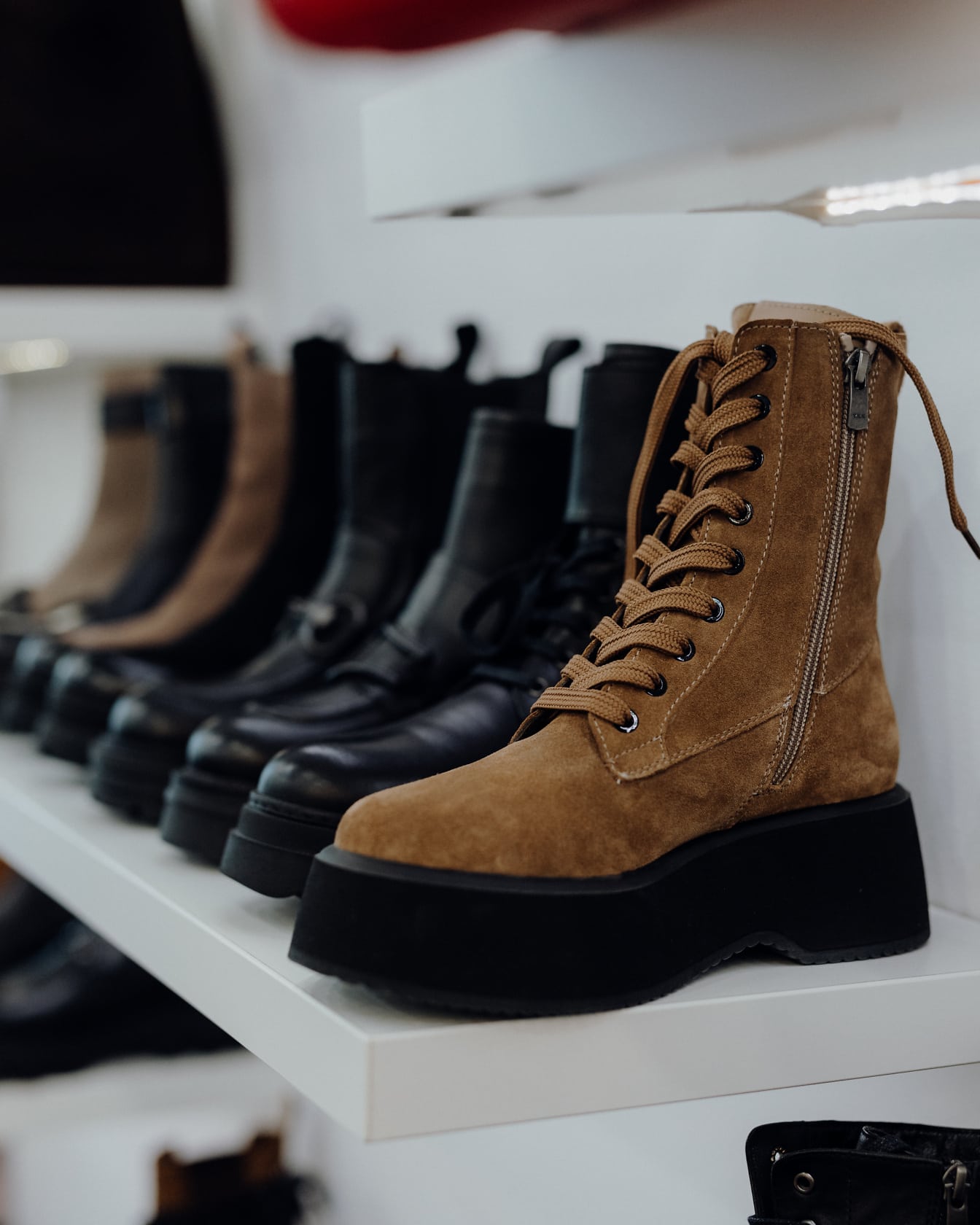Row of boots on a shelf with brown leather boot in foreground