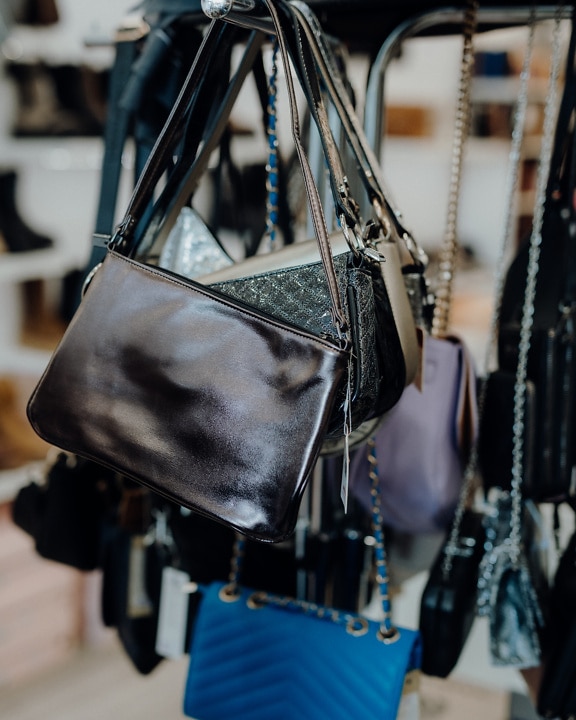 Various handmade leather purses hanging from a rack