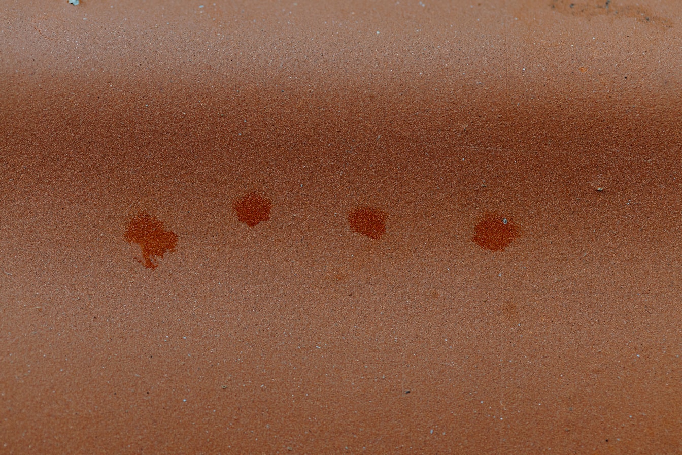 Gruppe mørkerøde flekkflekker på en rødaktig overflate