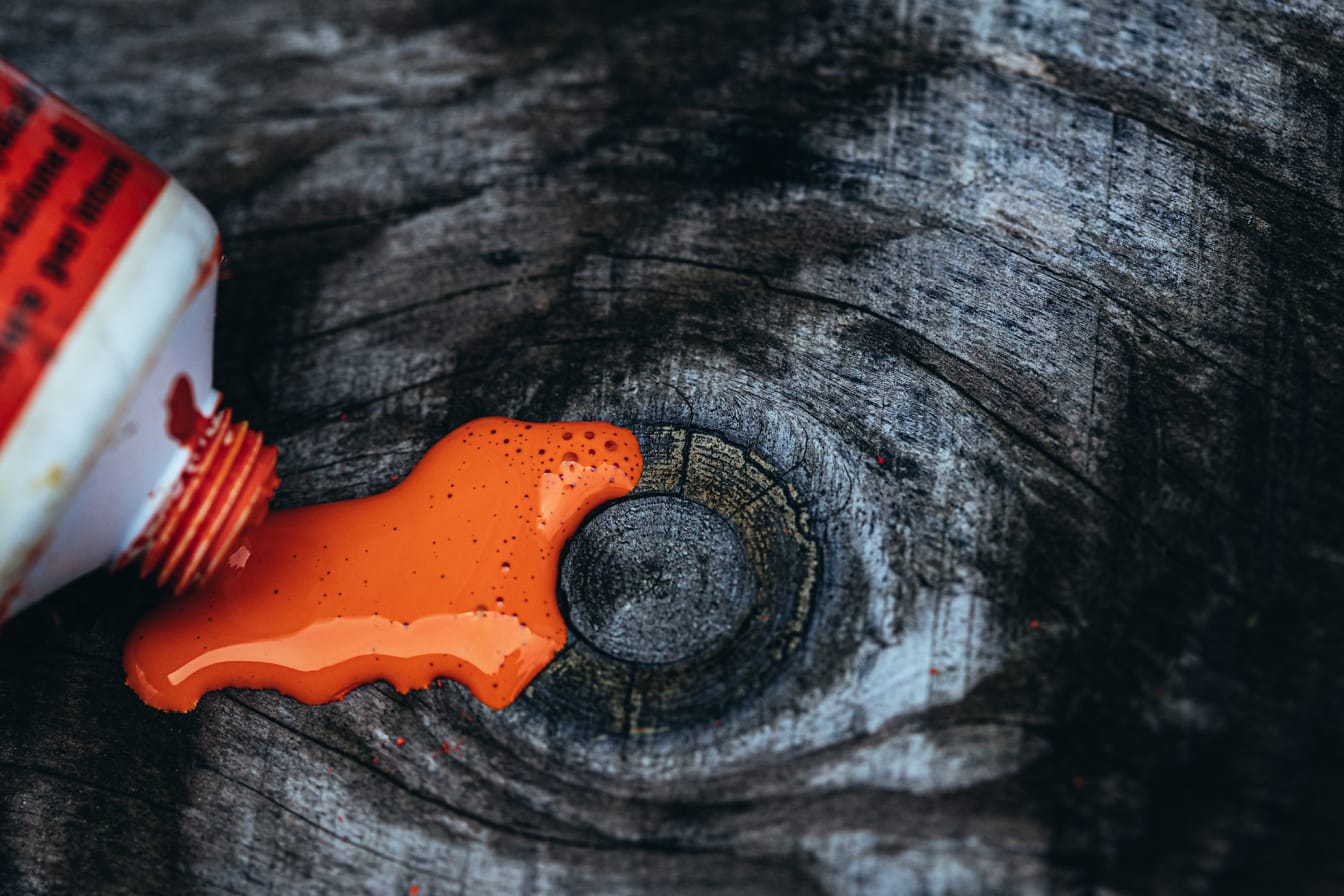 Vopsea acrilică portocalie vărsată pe o suprafață din lemn fotografie de aproape