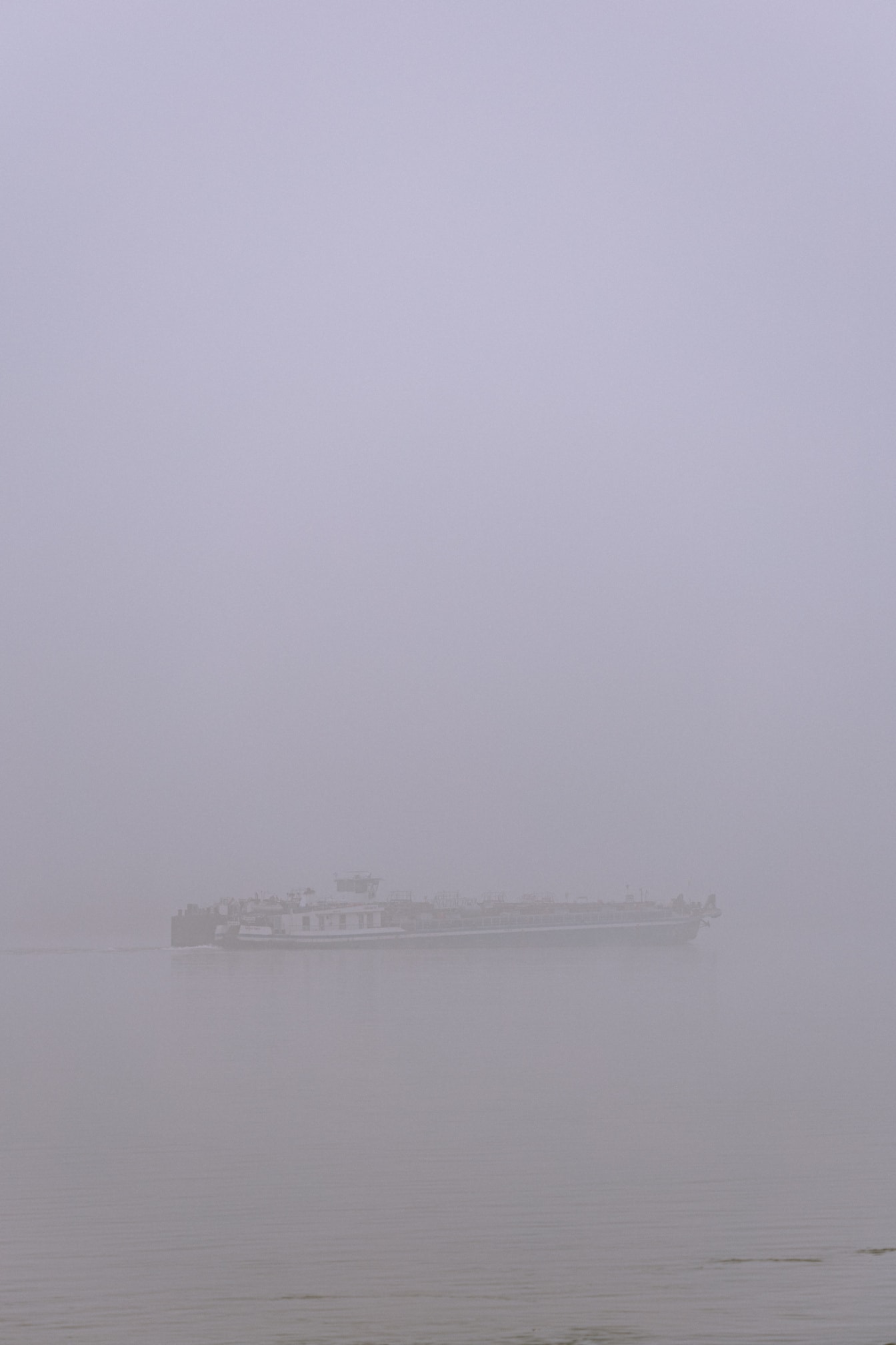 Pråmfartyg på floden i extremt tät dimma