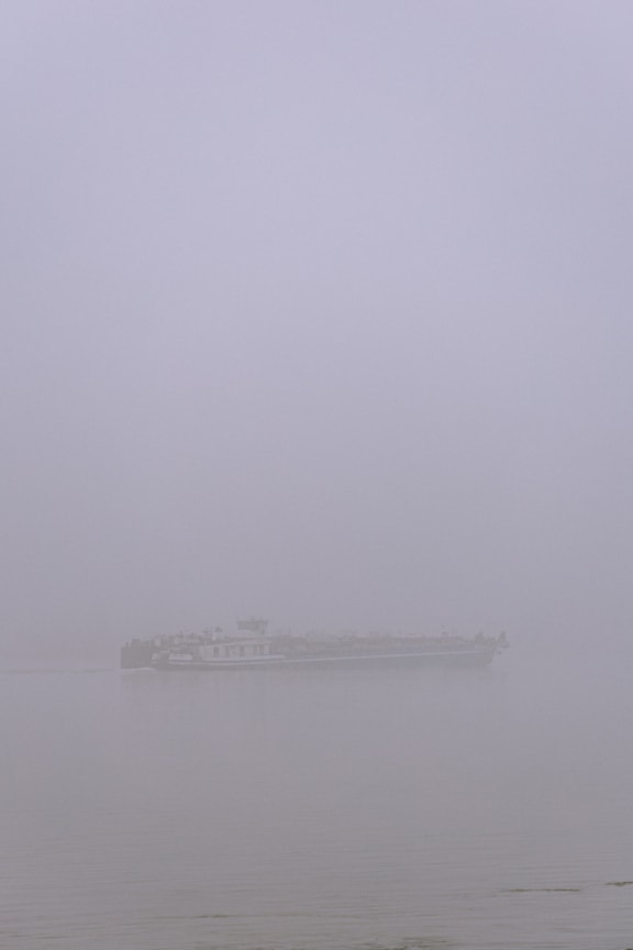 Barge ship on river in extremely dense fog