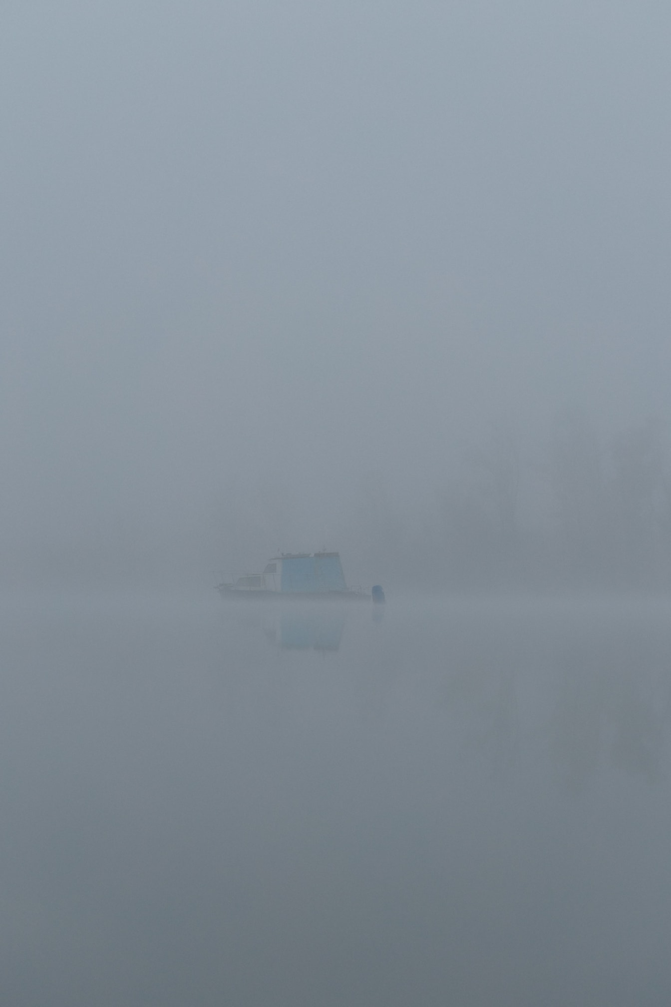 Barca in lontananza sul lago nella nebbia densa