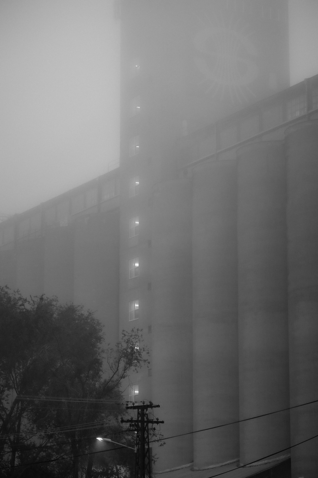 Foto en blanco y negro del edificio de silos de hormigón en la densa niebla