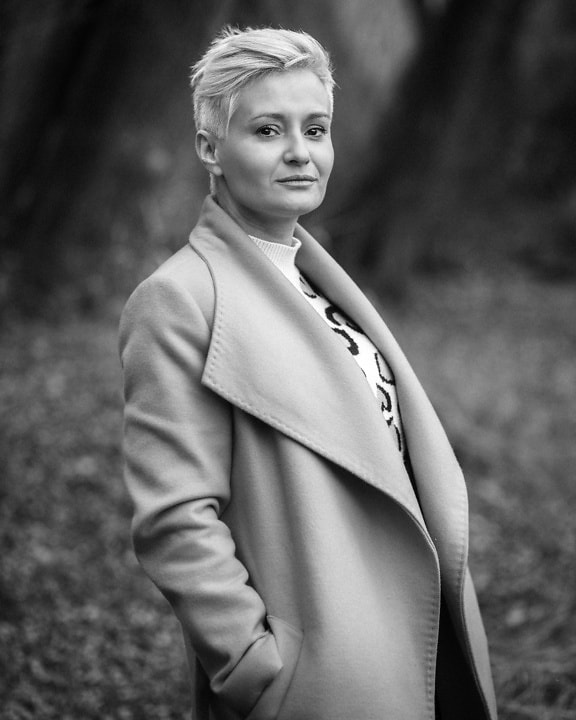 Black and white portrait of blonde woman with short hair wearing a coat