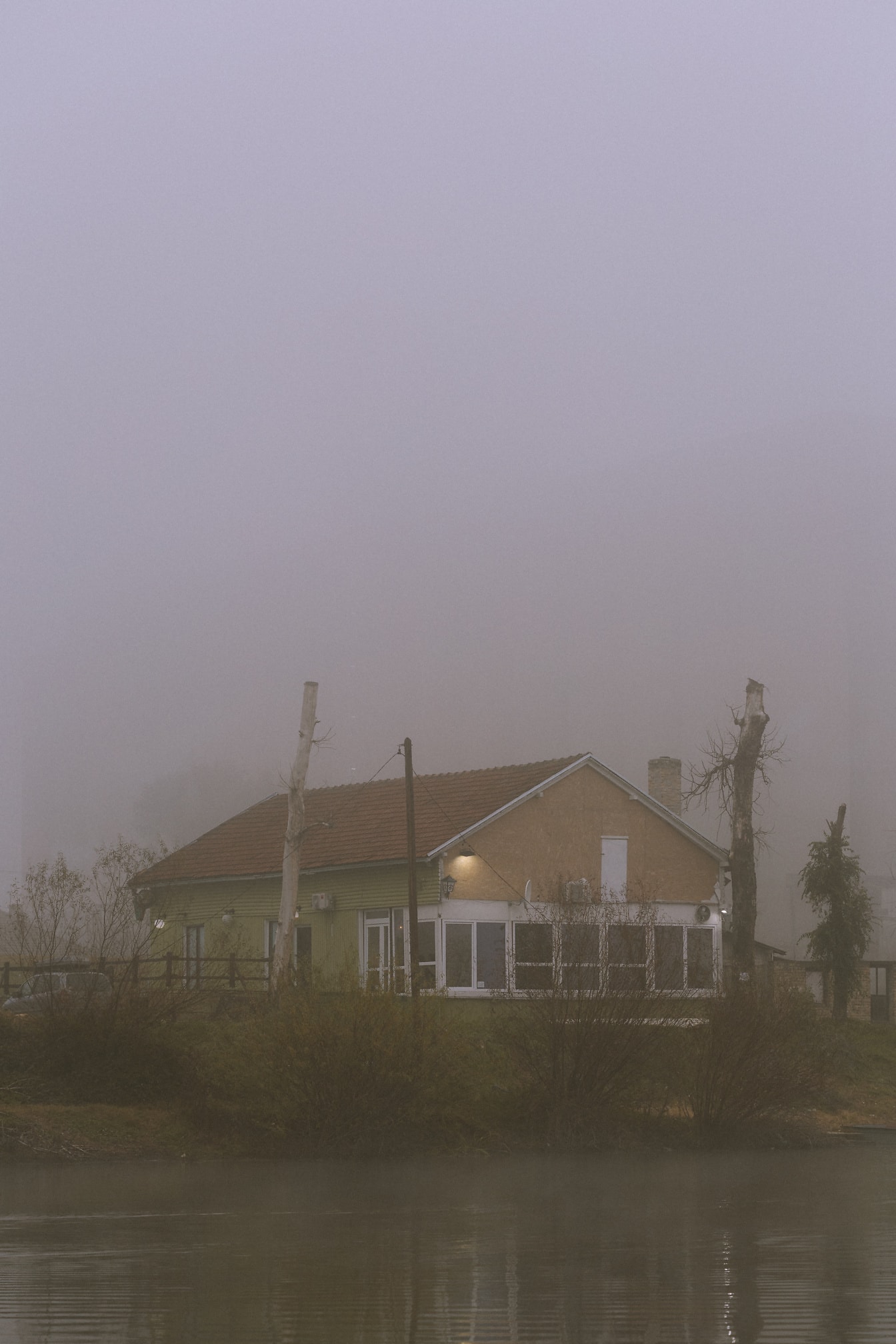 Rumah dalam kabut tebal dengan pepohonan di latar belakang