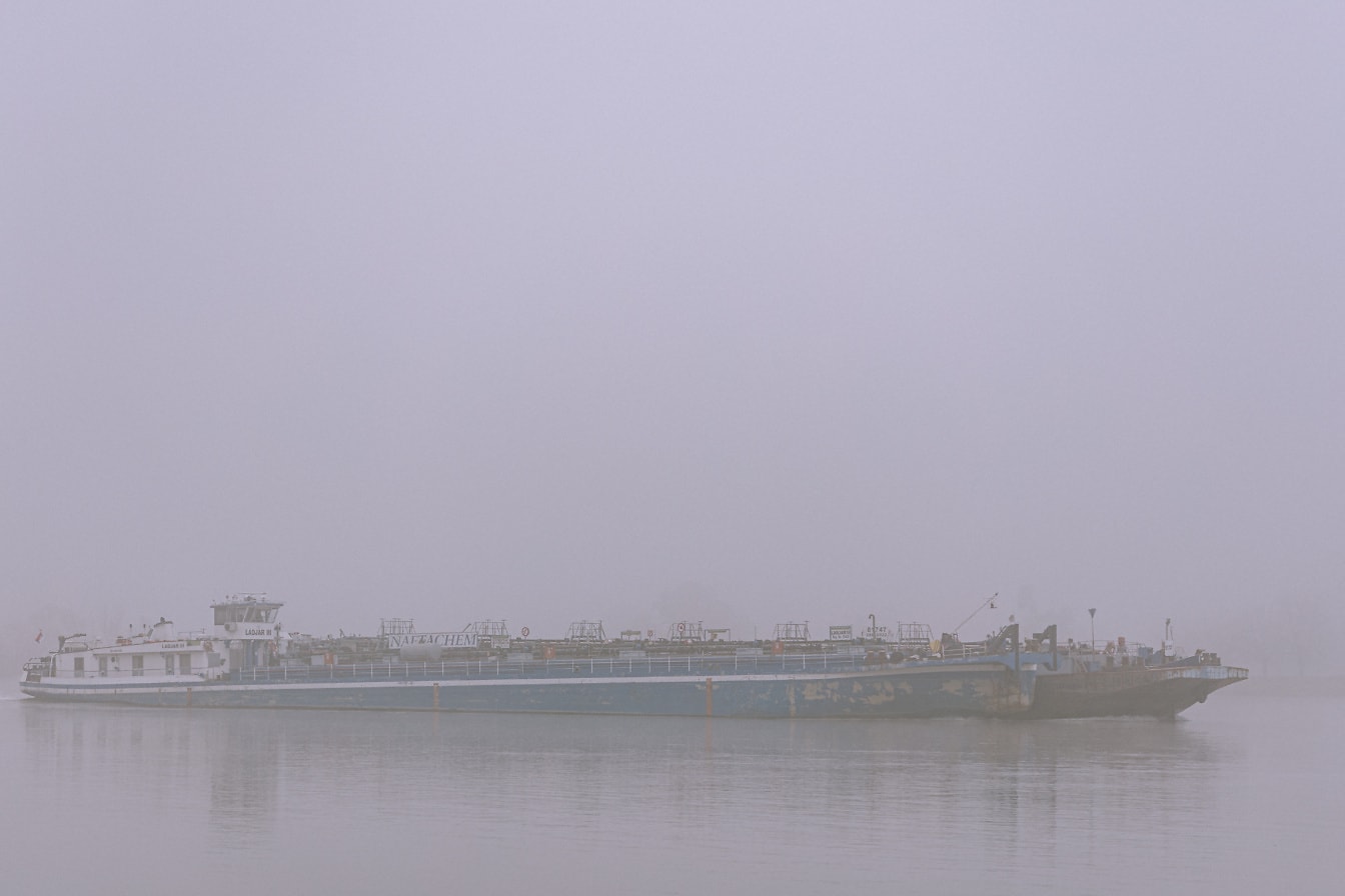 Side view of a large ship in the water at dense fog