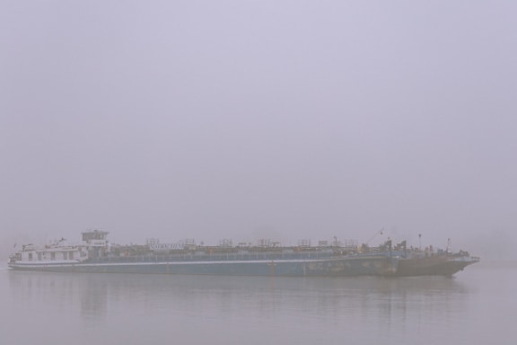 Seitenansicht eines großen Schiffes im Wasser bei dichtem Nebel
