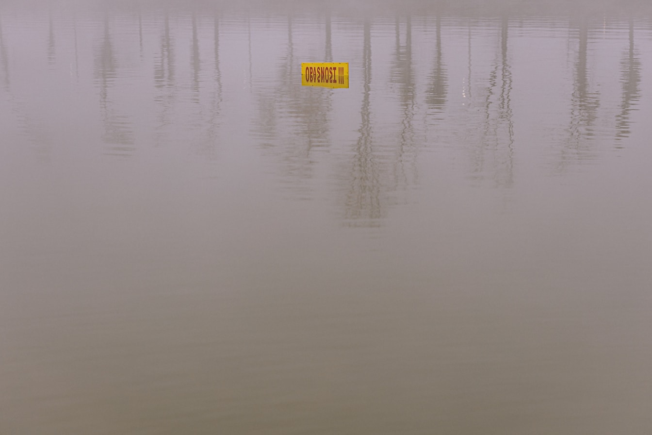 Warnschild gelbes Schild halb im Wasser untertauchen