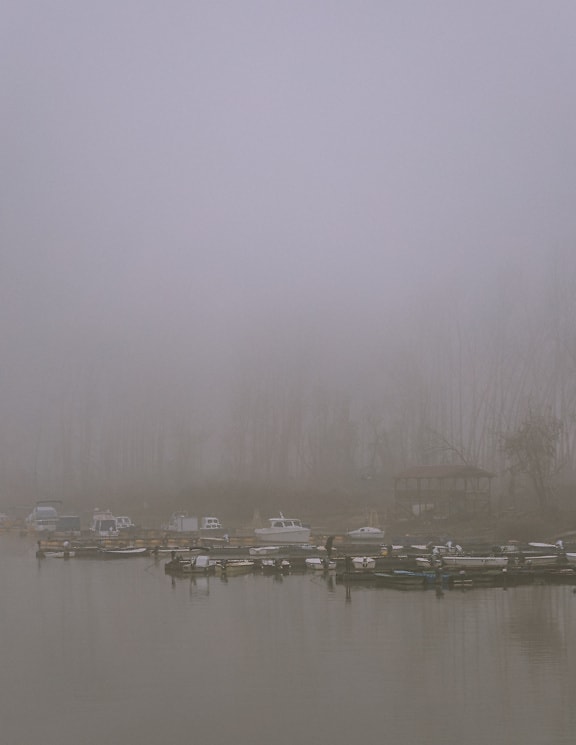 Small fishing boats on the water with dense fog
