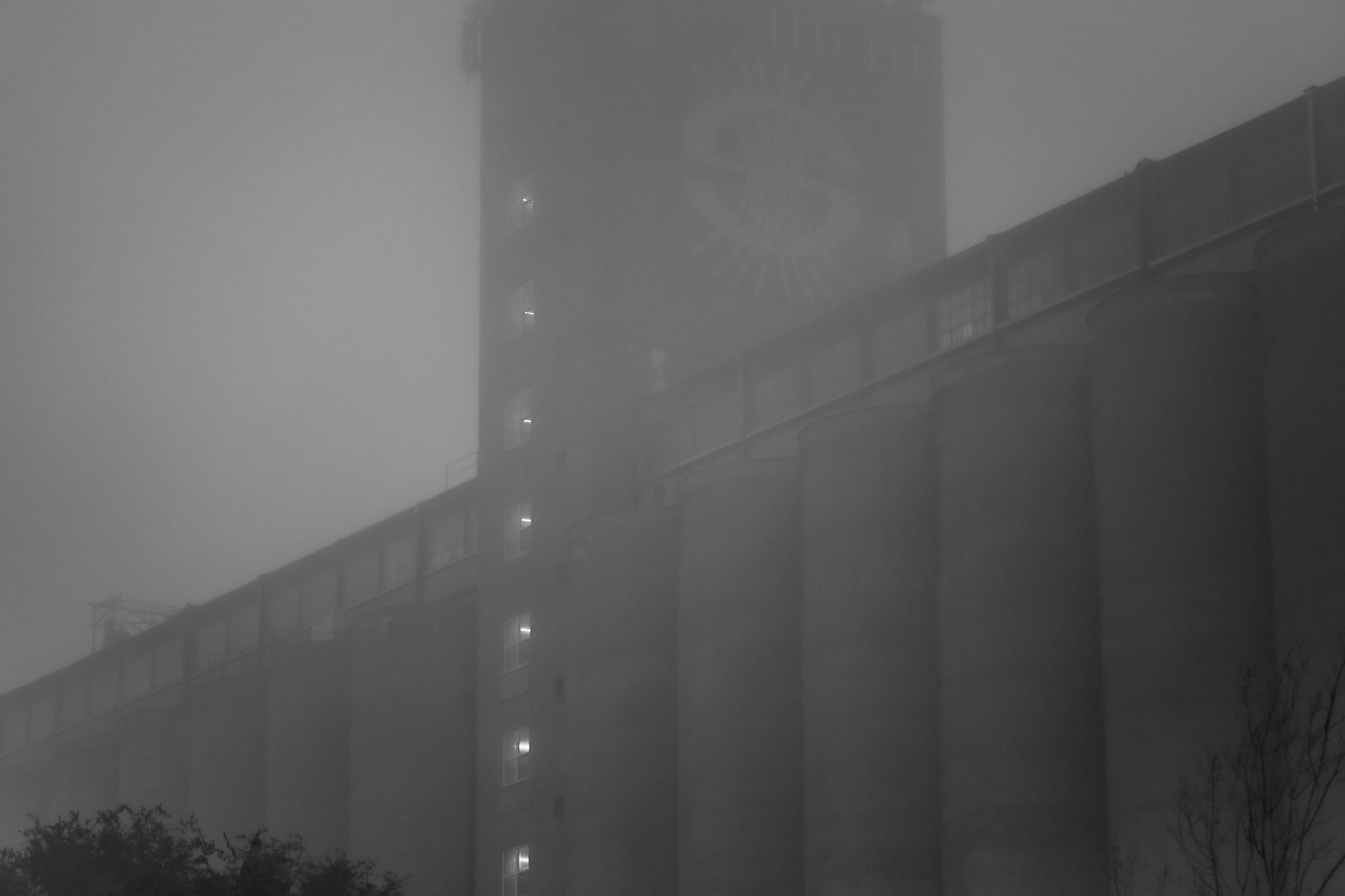Schwarz-weißes Silogebäude mit vielen Fenstern im Nebel
