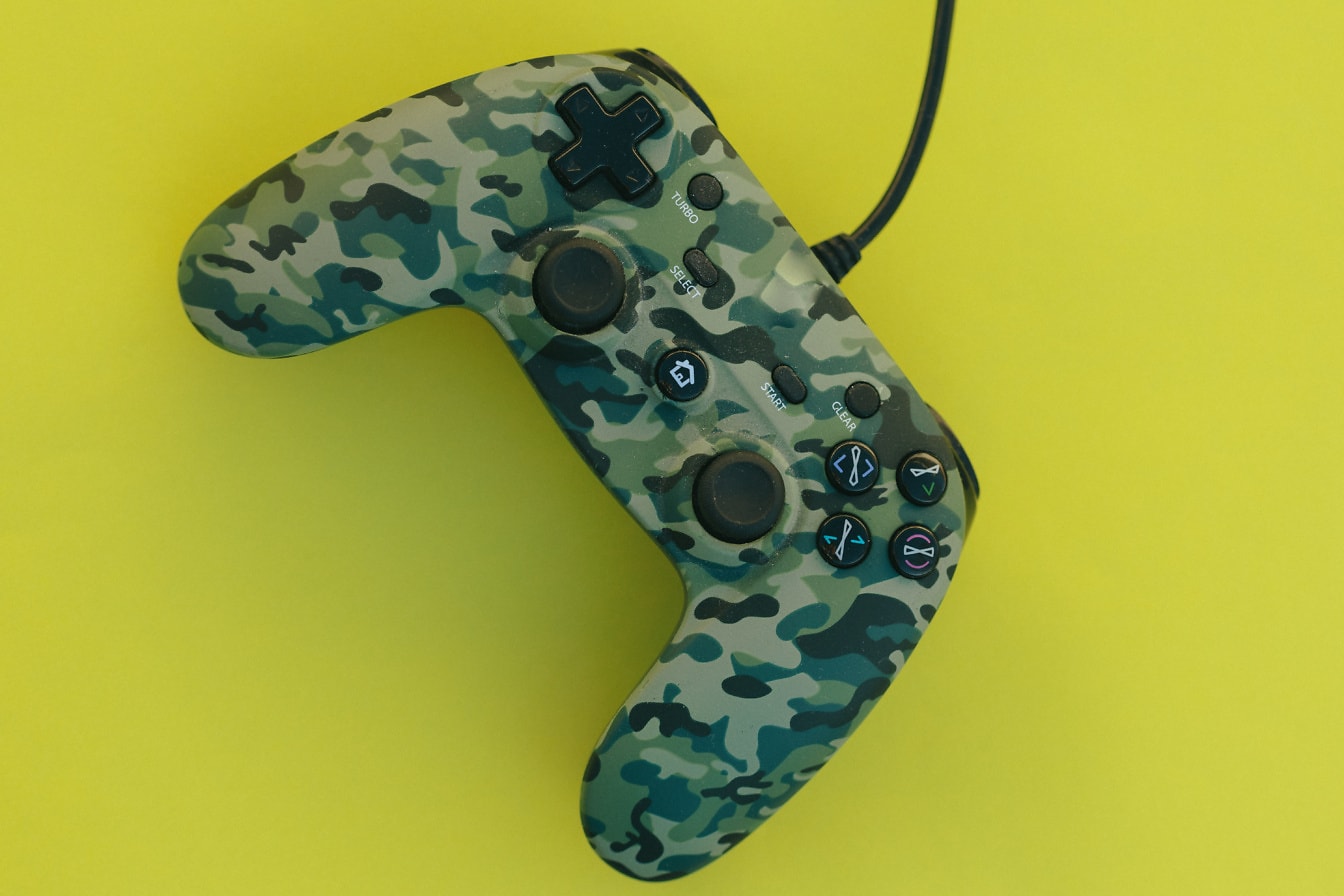 Videospelskontroll med tryckt militärt kamouflagemönster på den och med en sladd