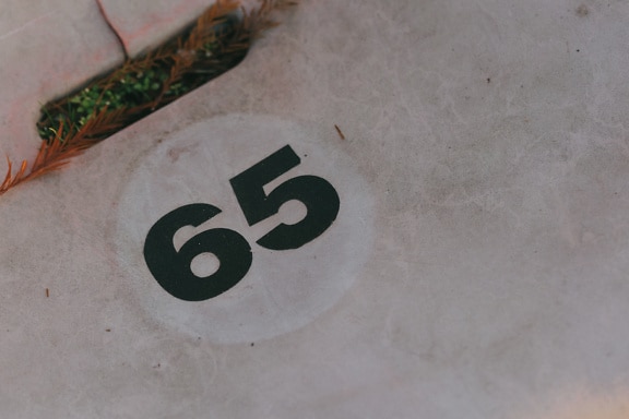 Número sessenta e cinco (65) em uma superfície de plástico bege