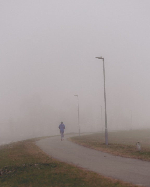 Osoba kráčející sama v mlhavém dni