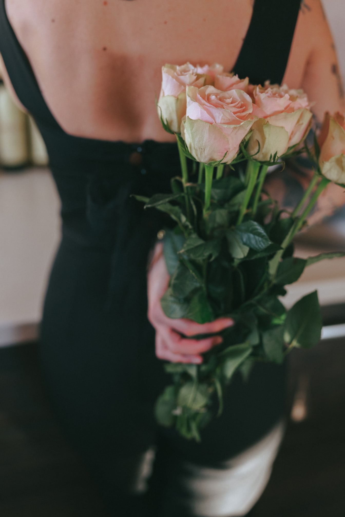 Nainen pitelee selässään kimppua vaaleanpunaisia ruusuja
