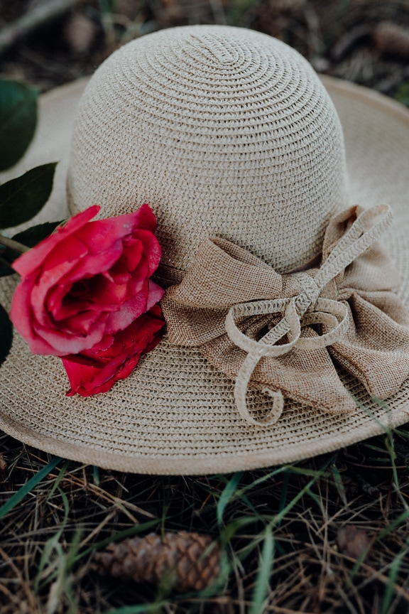 Modischer handgefertigter Hut mit einer rötlichen Rose darauf
