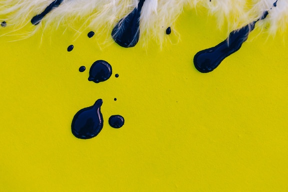 Black acrylic paint on a yellow surface close-up