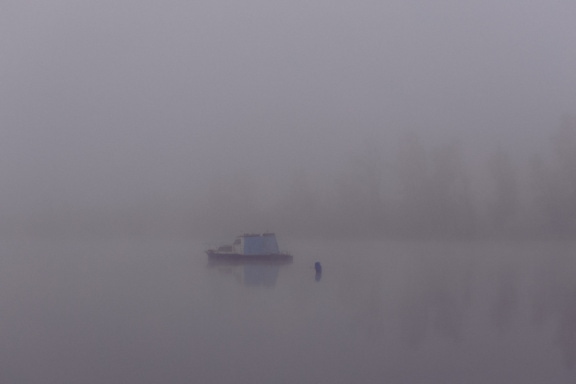 Liten fiskebåt i tät dimma