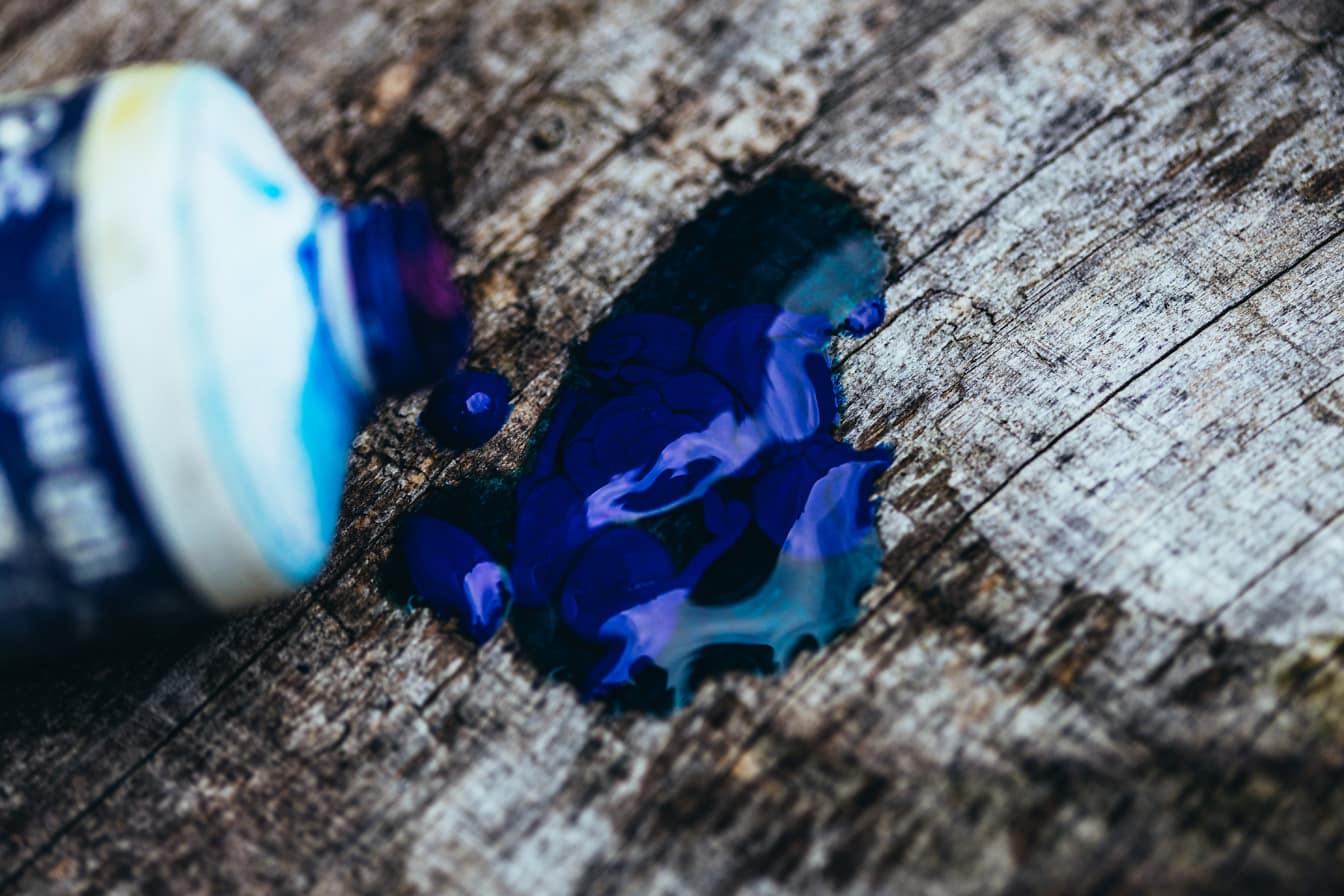 Tinta acrílica azul escuro derramada sobre uma superfície de madeira