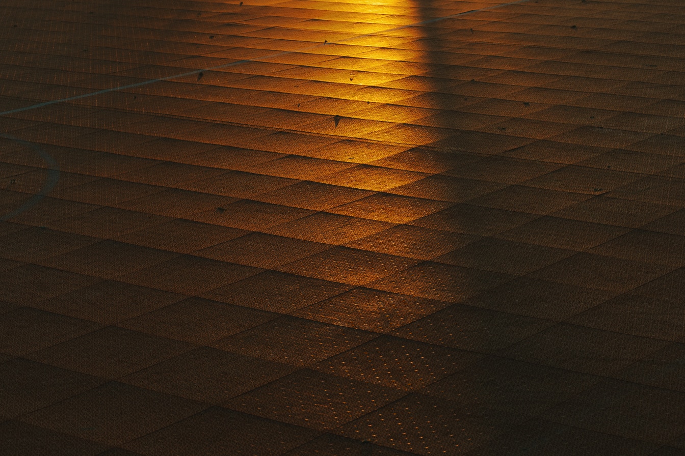 Oranžově žluté sluneční světlo svítící na dlážděnou podlahu
