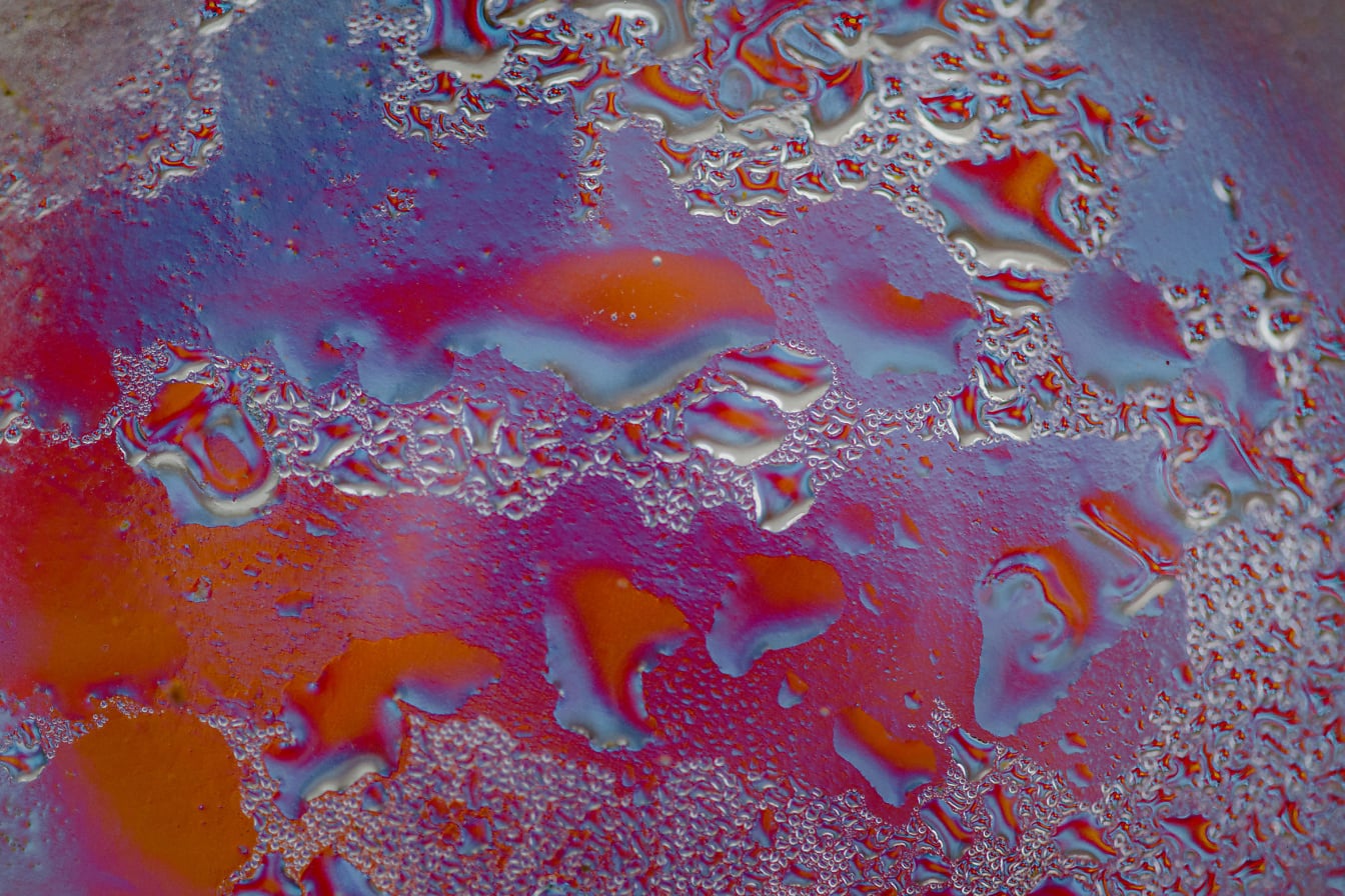 赤みを帯びた絵の具の上に凍った水滴の質感