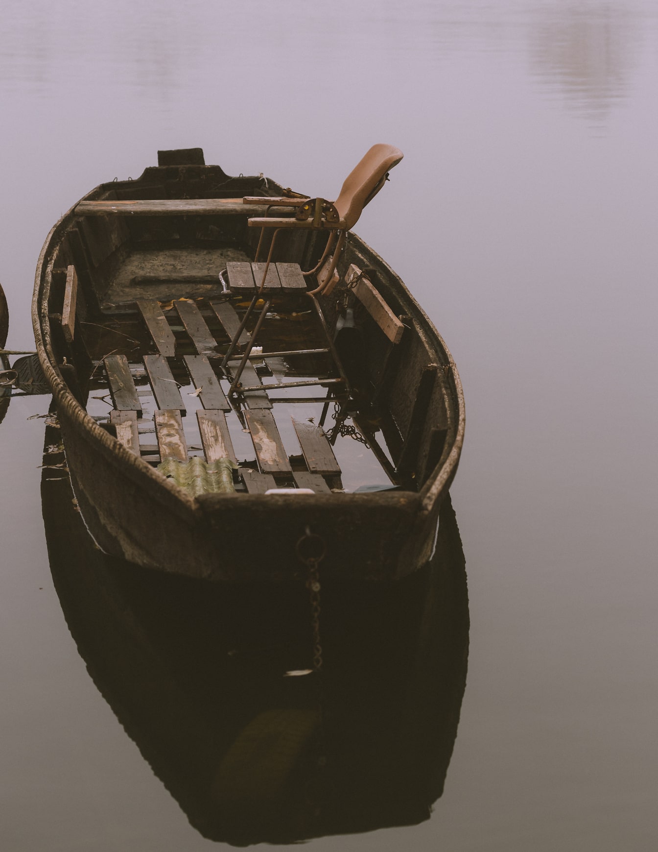 Old wooden boat on the water with chair in it
