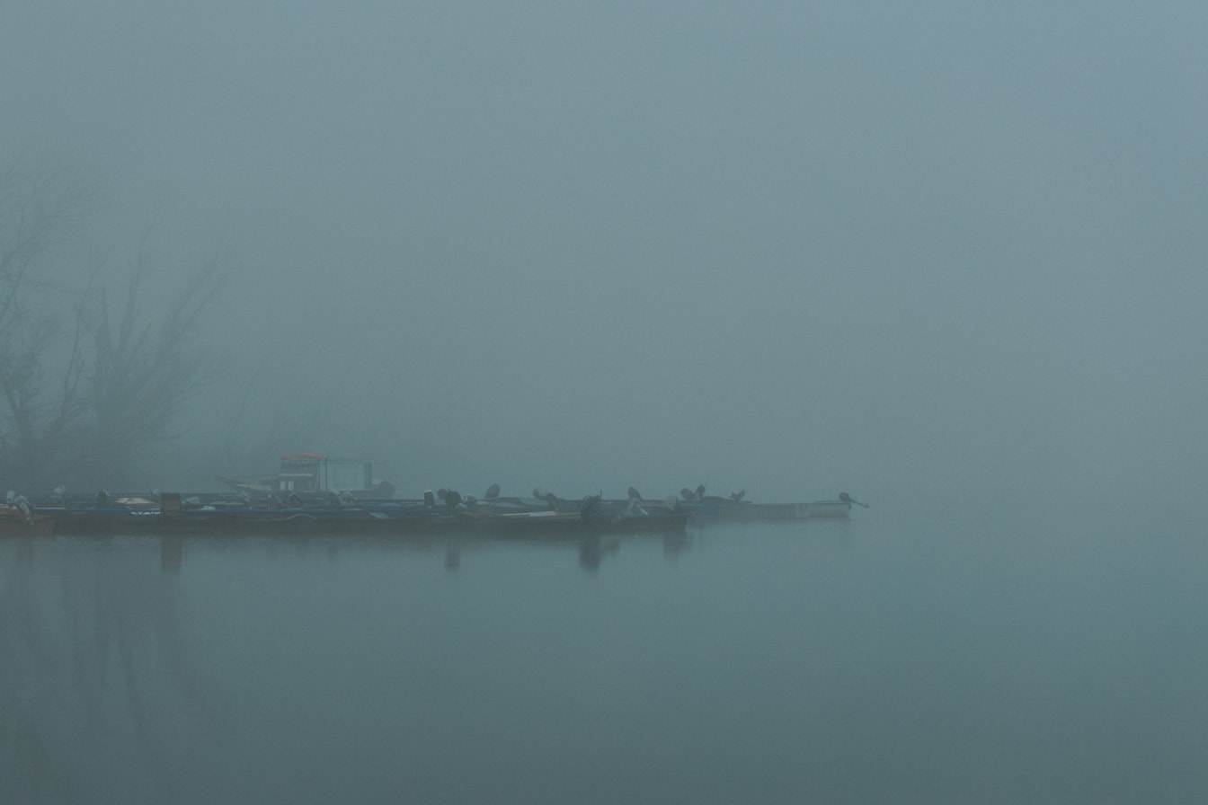 Dock with boats on Tikvara lake in the dense fog
