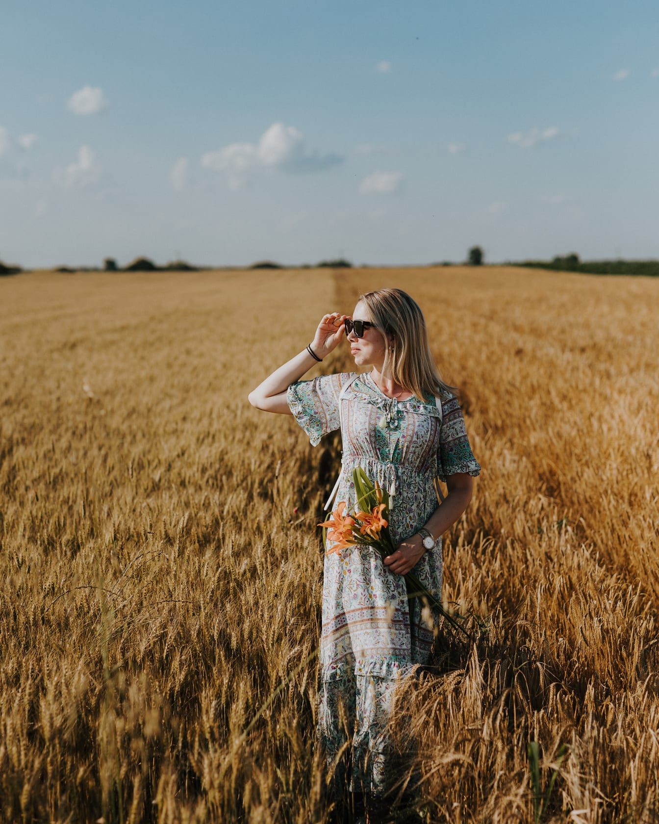 Upea maaseutu, nuori nainen kävelemässä vehnäpellolla kesällä