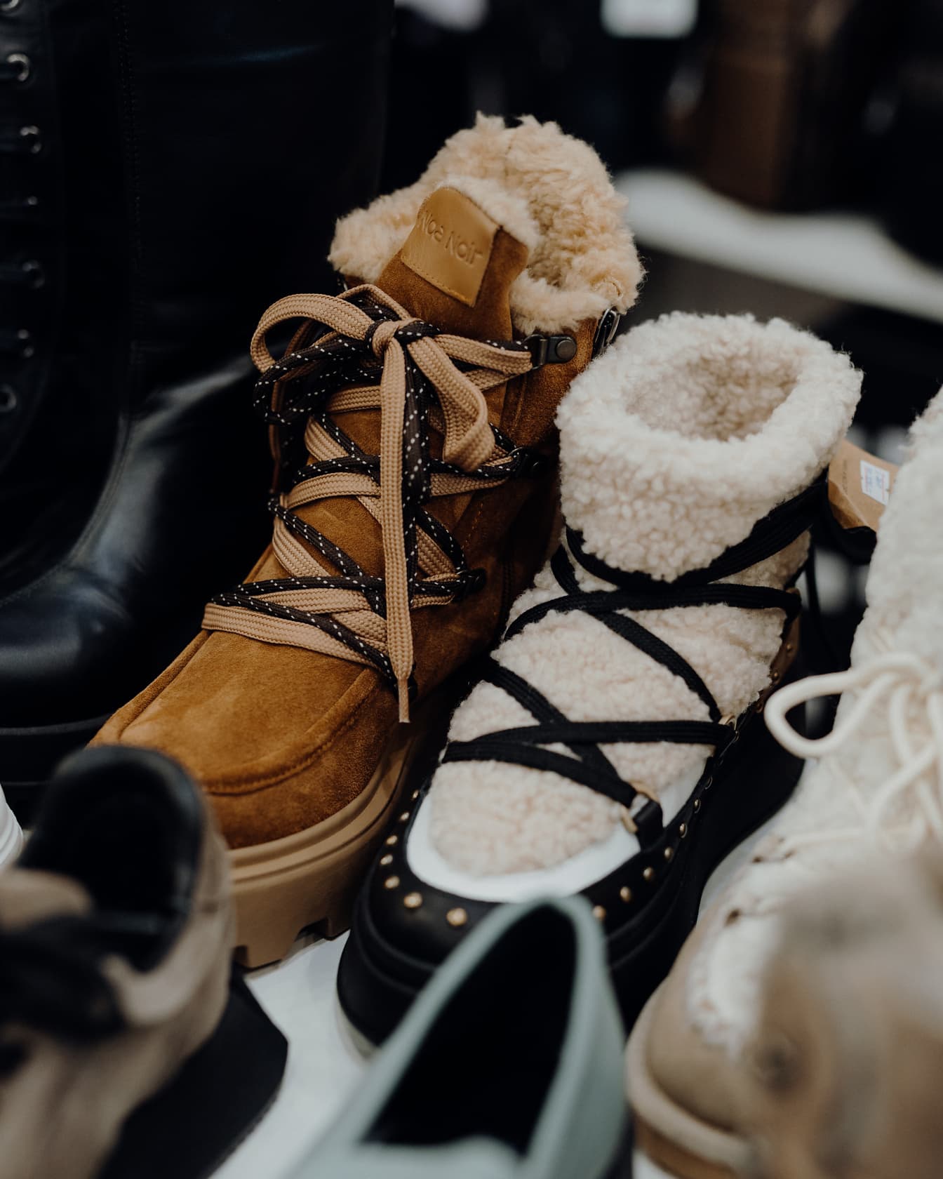 棚にファッショナブルな靴紐が付いた革の冬の毛皮のブーツ