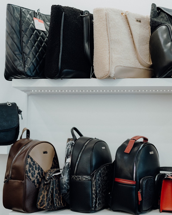 Ассортимент модных кожаных сумок на полках в магазине