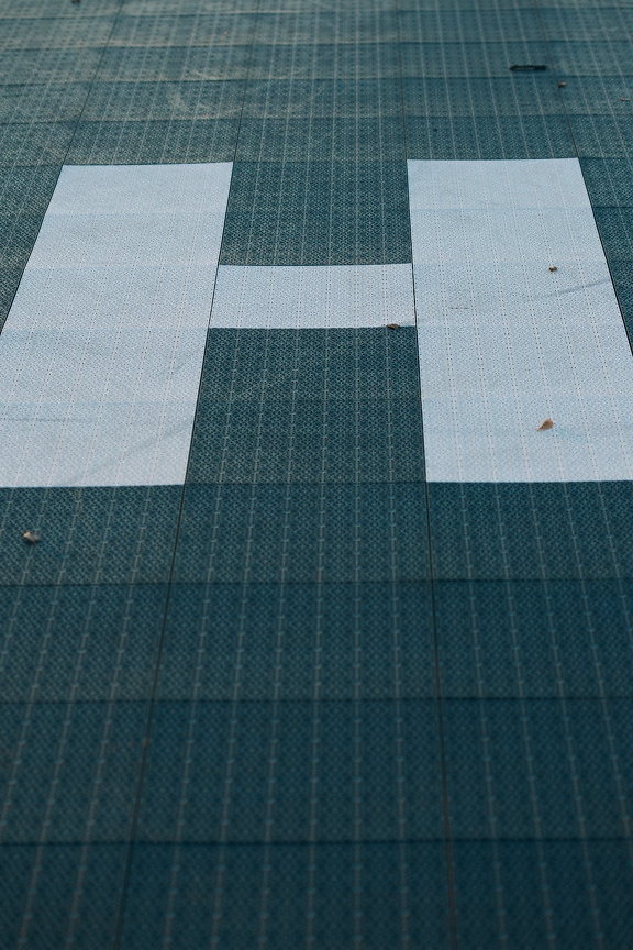 Textur der Kunststoffbodenoberfläche mit quadratischem Muster und mit dem Buchstaben H