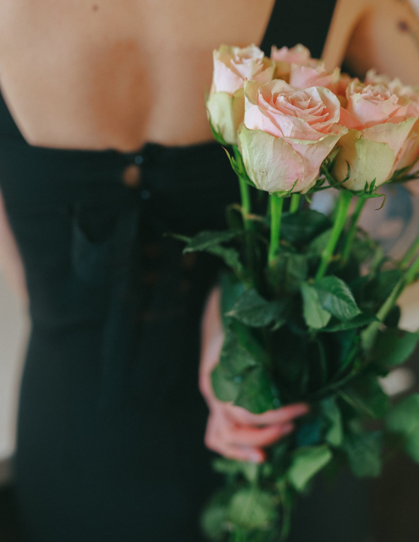 Wanita memegang buket mawar merah muda cerah di punggungnya